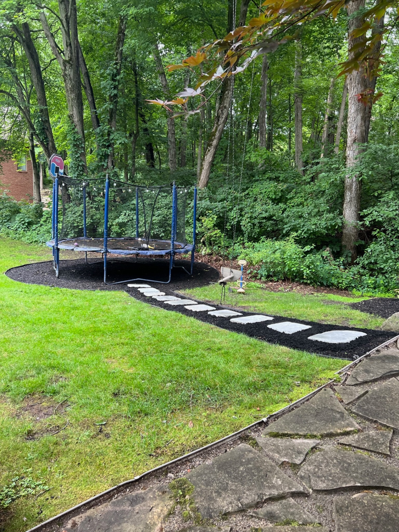 A curved stepping-stone path through a fresh mulch bed creates a finished route across the backyard.