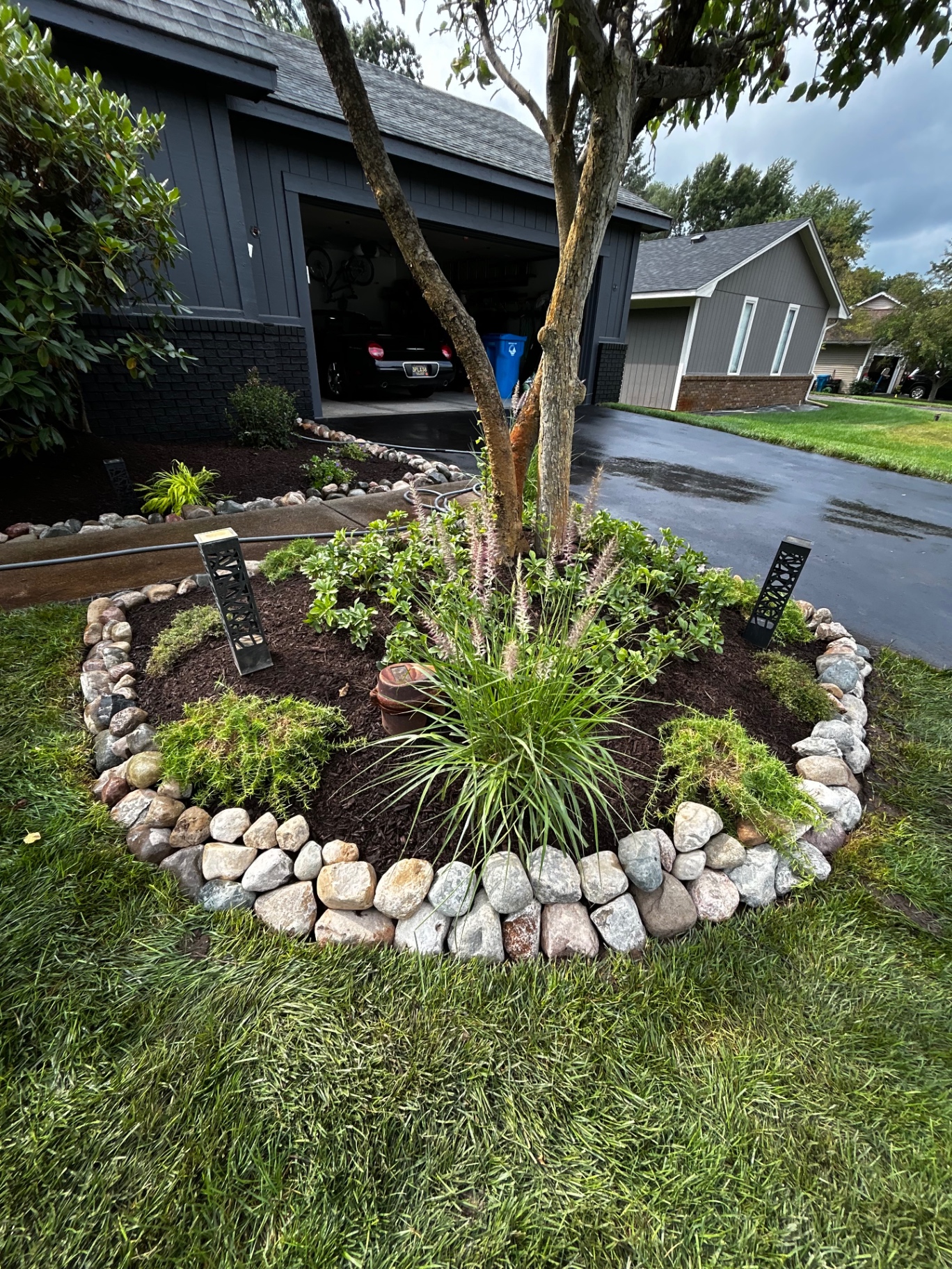 Rounded natural stone edging with fresh mulch and landscape lighting.