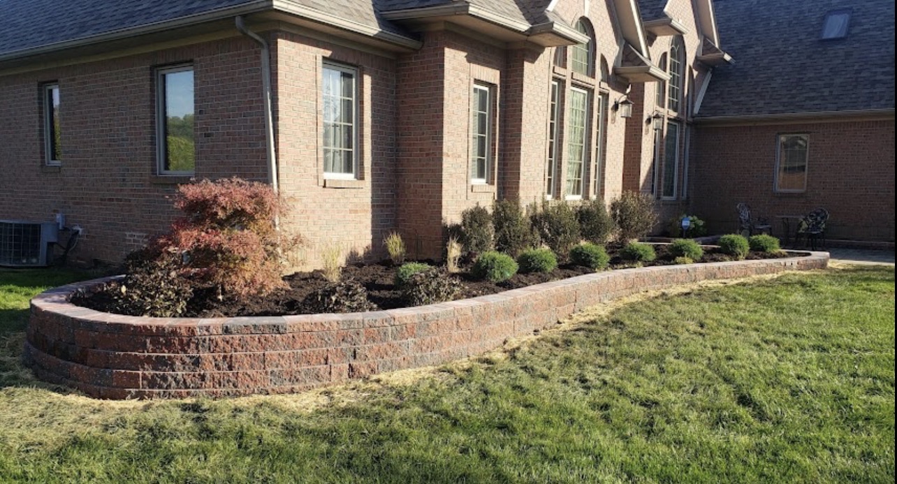 Segmental block retaining wall with new shrub plantings and mulch.
